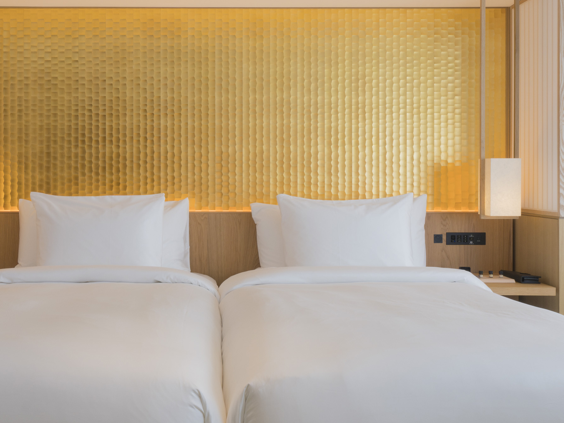 White twin beds rest under a textured golden wall, creating a cozy ambiance at Banyan Tree Higashiyama Kyoto.